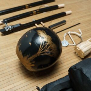 Close-up of the berimbau's hand-painted cabaca with a golden tree and bird design